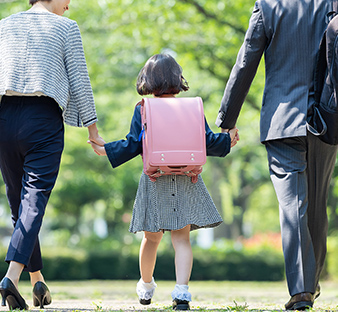 小学生の娘と手を繋いで歩く夫婦の写真